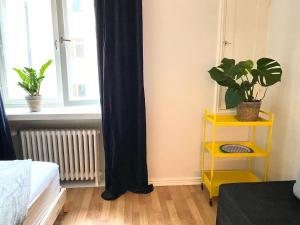 a room with a yellow shelf with plants and a window at Simply chic Kamppi !NEW! in Helsinki