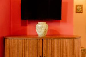 a vase sitting on a cabinet under a television at Yiayia's Guesthouse in Ýpsos