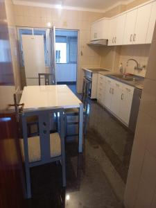 a kitchen with white cabinets and a blue table and chairs at Casa da Zendinha in Coimbra +14 photos