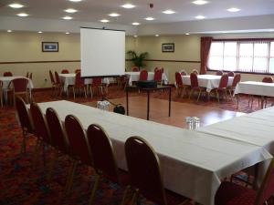 a conference room with tables and chairs and a white screen at Ayre Hotel & Ayre Apartments in Kirkwall