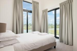 een slaapkamer met een bed en grote ramen bij The Cotswolds Manor ML26 Lower Mill Estate. in Somerford Keynes