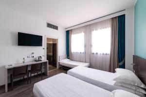 a hotel room with two beds and a desk at Phi Hotel Milano in Baranzate +38 photos