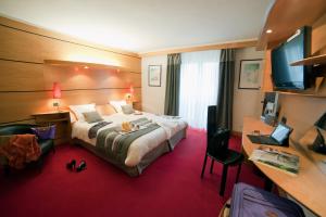 una camera d'albergo con un grande letto e una scrivania di Hotel & Résidence Les Vallées Labellemontagne a La Bresse