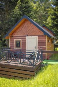a cabin with a deck and a white door at Domki Całoroczne Jaga in Skorka