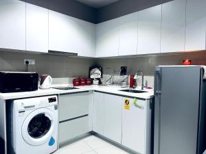 a kitchen with white cabinets and a washer and dryer at Maple Homes at i-City - WiFi TV Box and 1 Carpark in Shah Alam