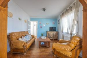 a living room with two leather chairs and a table at Le Bassin in Port-en-Bessin-Huppain