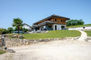 a house with a stone retaining wall and a driveway at Gite la Quintessence in Nonglard
