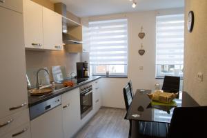 a kitchen with white cabinets and a dining table at Ferienhaus Borneich in Schwalbach