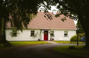 une maison blanche avec une porte rouge dans l'établissement Longford Holiday Red Rose Self Catering Cottage, à Longford