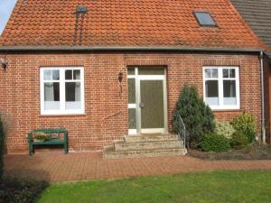 a brick house with a door and a green bench at Ferienhaus Fegebank in Nienhagen in Nienhagen