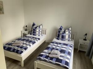 two beds with blue and white striped pillows in a room at Ferienhaus Fegebank in Nienhagen in Nienhagen