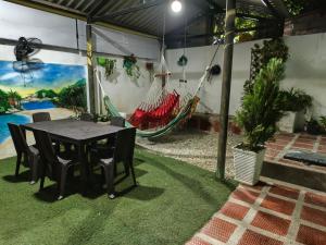 Un patio con mesa y sillas y una hamaca. en Casa alojamiento las acacias, en Santa Marta