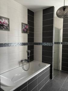 a bath tub in a bathroom with black and white tiles at Superbe villa 6 personnes proche océan et lac in Linxe