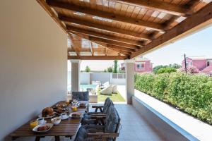 a patio with a wooden table and chairs on a roof at Luxurious Agios Georgios Villa Private Pool Villa Spyridoula Beach Paradise in Agios Georgios