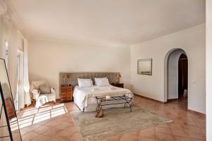 a white bedroom with a bed and a table at Dazzling Almancil Villa Villa Magorian 4 Bedrooms Spacious Furnished Sun Terrace Private Outdoor Pool Bbq Facilities Shaded Outdoor in Almancil +31 photos