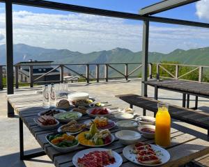 a table filled with plates of food with mountains in the background at Alpina Hotel in Gudauri