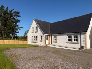 a white house with a black roof and a driveway at Gellyburn Cottage in Kinross