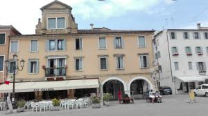 een groot gebouw op een straat met tafels en stoelen bij B&B Antico Orologio in Chioggia