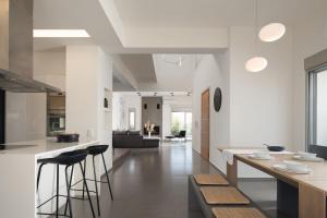 a kitchen and living room with white walls and bar stools at Extravagant Crete Villa 4 Bedrooms Villa Yasemí I Private Pool And Outdoor Amenities Bbq Rethymno in Prínos