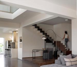 a staircase in a living room with a woman walking up the stairs at Extravagant Crete Villa 4 Bedrooms Villa Yasemí I Private Pool And Outdoor Amenities Bbq Rethymno in Prínos +15 photos