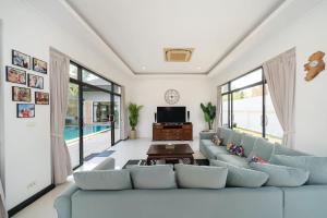 Una sala de estar con un sofá azul y un televisor. en Bua Sawan - 4 Bedrooms Pool Villa, en Ban Pak Lak