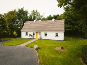 uma pequena casa branca com um quintal e uma entrada para carros em Longford Holiday Yellow Star Self-Catering Cottage em Esker South