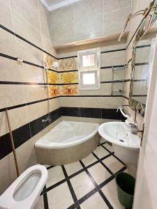 a bathroom with a tub and a toilet and a sink at فيلا اول صف بحر مارينا الساحل الشمالي العلمين برايفت بول in El Alamein