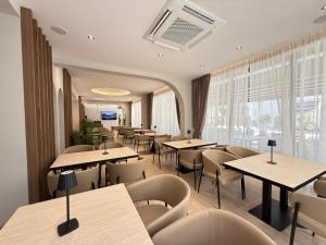ein Restaurant mit Tischen und Stühlen und einem großen Fenster in der Unterkunft Noam Luxury Hotel in Sarandë