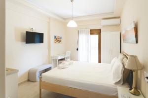 a white bedroom with a bed and a tv at Alcentro Studio 1 in Platamonas