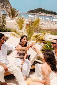 a group of people sitting around a table with drinks at Cala San Miguel Ibiza Resort, Adults only, Curio Collection by Hilton in Puerto de San Miguel