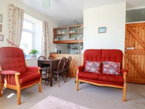 a living room with two red chairs and a table at Chyancrowse in Penzance +8 photos