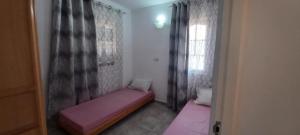 a small room with a pink bed and a window at TIBA résidence in Houmt Souk