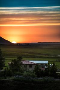 a house in a field with the sunset in the background at Breidamyri Farm Apartments in Laugar
