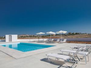 ein Swimmingpool mit Liegestühlen und Sonnenschirmen in der Unterkunft Villa Ioanni Chrysos - Luxury And New 6 Bedroom Protaras Villa in Protaras