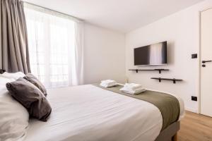 a bedroom with a large bed with a television on the wall at Au Chat Qui Dort Lille - Archives 3 in Lille