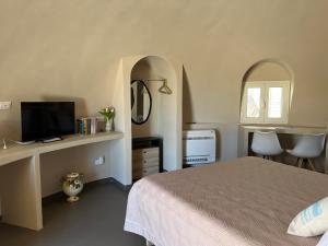 una camera da letto con un letto e una scrivania con una televisione di Nausicaa Guesthouse a Marsala