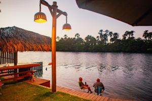 a couple of people sitting on a dock near the water at Vila dos Poetas - 02 quartos - GD in Barreirinhas