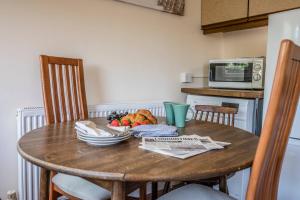 a wooden table with a bowl of fruit on it at Everglades, Reydon in Reydon +13 photos