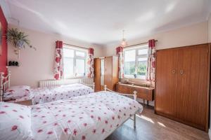 a bedroom with two beds and a dresser and two windows at Everglades, Reydon in Reydon