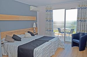 - une chambre avec un lit, une chaise et un balcon dans l'établissement Logis Hotel Solhotel, à Banyuls-sur-Mer