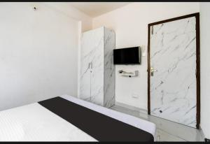 a white bedroom with a bed and a tv at Bluestone Residence in Pānchuria