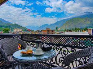 a table with food and coffee on a balcony at Click Hotel Bhuntar, Kullu Manali -Bhuntar Airport in Bajaura