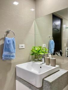 マニラにあるCozy place across Mitsukoshi Mallの白い洗面台と鏡のあるバスルーム