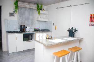 a kitchen with white cabinets and a counter with stools at Optimum Stay Self Catering Accommodation - Junior Suite in Parow
