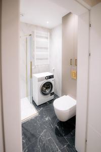 a bathroom with a toilet and a washing machine at obywatelska apartament free parking KLIMA in Łódź +4 photos