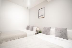 a white bedroom with two beds and a picture on the wall at Brand New Luxury Suite 7 min to Omotesando 2 min to Shibuya in Tokyo
