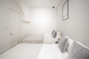 a white bedroom with two beds and a window at Brand New Luxury Suite 7 min to Omotesando 2 min to Shibuya in Tokyo