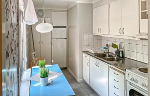 a kitchen with white cabinets and a blue table with a plant at 2 Bedroom Stunning Home In Klintehamn in Klintehamn