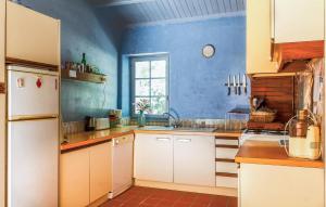a kitchen with white cabinets and a blue wall at Amazing Home In La Boissières Des Land in Saint-Avaugourd-des-Landes +13 photos