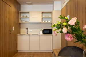 a kitchen with white cabinets and pink flowers at Wolska Residence I in Warsaw +42 photos